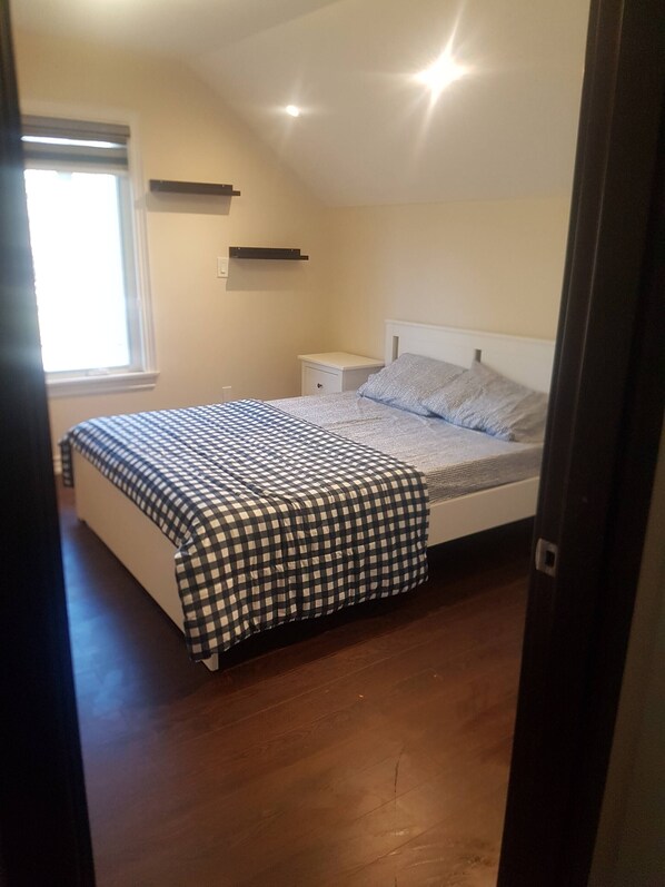 A bedroom with a bed, a nightstand, a window, and a ceiling light.