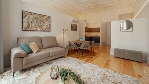 A living room with a beige sofa, a coffee table with plants, a dining area with a round table and chairs, and a kitchen in the background. - Heart OF Porto Apartment A by Vacationy (Porto)