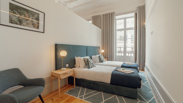 A modern hotel room with a large bed, a chair, a desk, and a window with curtains. - Heart OF Porto Apartment A by Vacationy (Porto)