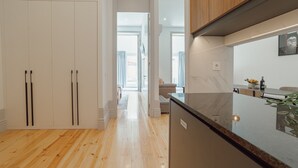 A modern kitchen with wooden cabinets, a marble countertop, and a view to the living area.
