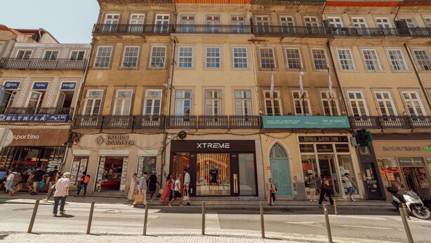 A multi-story building with various storefronts, including a visible pharmacy and a clothing store.