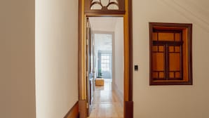 A hallway with wooden flooring and a door with a window.