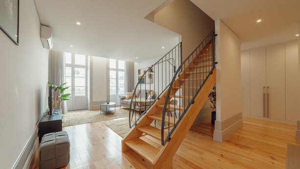A spacious living area with a wooden staircase, a sofa, and a coffee table.