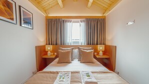 A hotel room with a large bed, two bedside tables with lamps, a window with curtains, and framed pictures on the wall. - Heart OF Porto Apartment F Duplex by Vacationy (Porto)