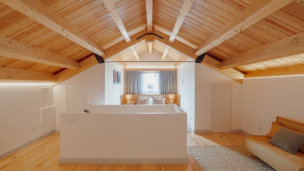 A spacious attic bedroom with a large white bathtub, wooden beams, and a view of a balcony. - Heart OF Porto Apartment F Duplex by Vacationy (Porto)