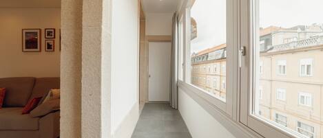 A narrow corridor with a view of buildings through a large window.