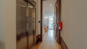 A hallway with a metallic elevator, wooden flooring, and a fire extinguisher mounted on the wall. - Heart OF Porto Apartment F Duplex by Vacationy (Porto)