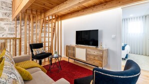 A modern living room with a wooden ceiling, a flat-screen TV, a sofa, a chair, and a red rug. - City Center Comfort Apartment B by Vacationy (Porto)