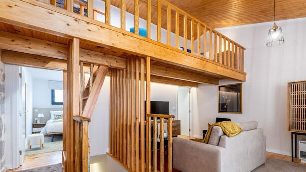 A spacious loft with a wooden staircase, a grey sofa, and a television in the background. - City Center Comfort Apartment B by Vacationy (Porto)