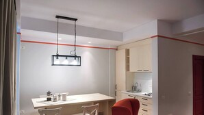 A modern kitchen with white cabinets, a white countertop, and a red chair. - Wave 1 Promenada Apartments (Navodari)