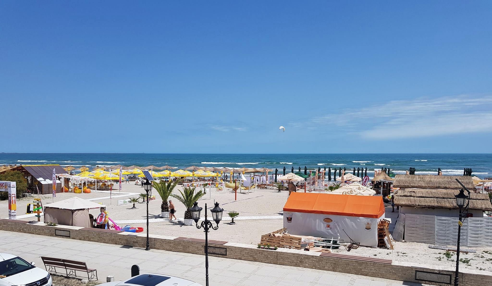 Una zona sulla spiaggia con ombrelloni, un piccolo edificio e vista sull'oceano.