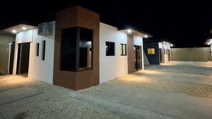 A modern building with multiple entry points, each illuminated by overhead lights. - Residencial Fe y Esperanza (Pedernales)