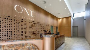 A modern reception area with a wooden wall and a large 'ONE ROSEBANK' sign.