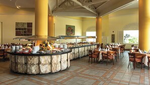 Ein Buffet mit Steintresen, mehreren Esszimmertischen und Stühlen.
