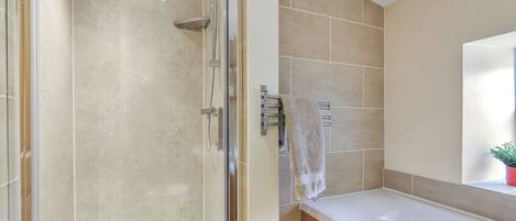 A modern bathroom with a glass-enclosed shower, a wooden vanity, and a large mirror above the sink.