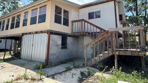 Ein zweigeschossiges Haus mit Garage, einer Holztreppe und einer Veranda.