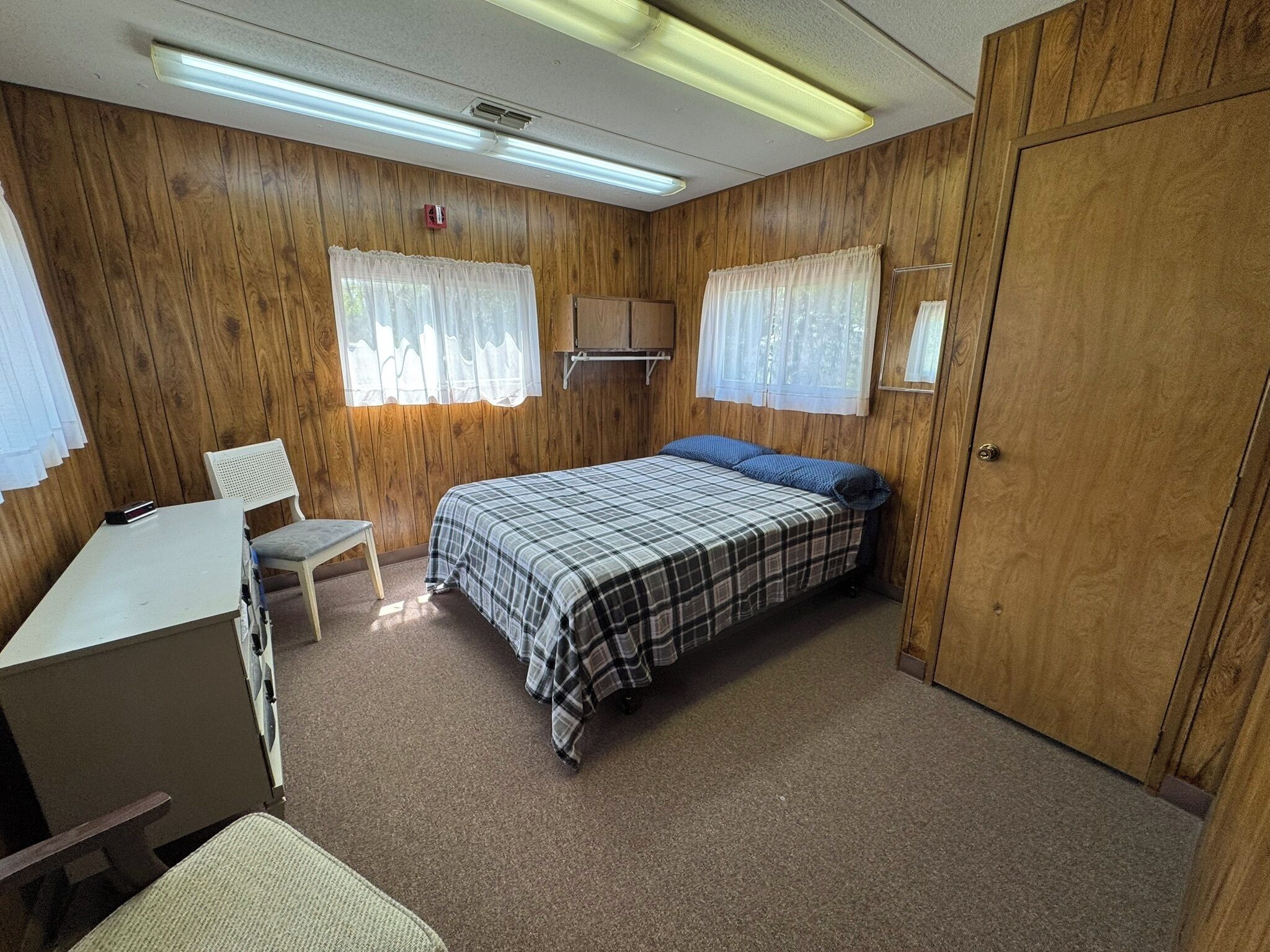 A compact room with a bed, a desk, and a chair.