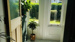 A sunlit room with a patterned floor, a potted plant, and a view of a garden through a window. - Spacious family-friendly & pet-friendly Victorian home in bustling east Belfast (Belfast)