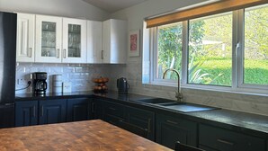 A modern kitchen with dark cabinets, a wooden countertop, and a window with a view of greenery. - Spacious family-friendly & pet-friendly Victorian home in bustling east Belfast (Belfast)