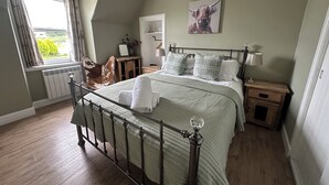 Een slaapkamer met een bed, een raam, een stoel, een nachtkastje en een lamp.