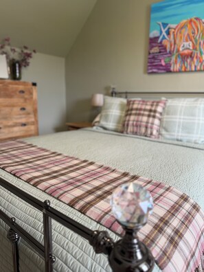 A bed with a plaid bedspread and a decorative crystal on the headboard. - Knockenhooley is a beautiful traditional cottage on the magical Isle of Skye (Isle of Skye)