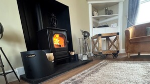 Un salon doté d’une cheminée, d’un plancher en bois et d’un tapis à motifs.