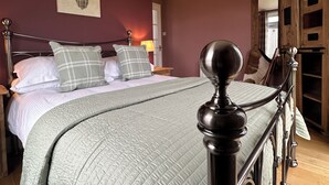 Une chambre à coucher comprenant un lit, une tête de lit, une décoration murale représentant une tête de cerf, une porte en bois et un luminaire au plafond.