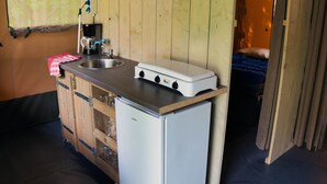A compact kitchenette with a small refrigerator, a stove, and a sink. - Camping 2000 - Safaritent Medium (Osecná)