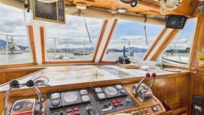 A boat's control station with multiple gauges, levers, and a steering wheel.