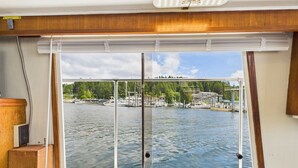 A boat's interior with a large window overlooking a marina, a sink, and a wooden cabinet.