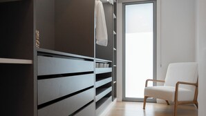 A modern room with a built-in wardrobe, a white chair, and a large window. - White Apartment (Funchal)