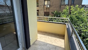 A balcony with tiled flooring, a metal railing, and a view of neighboring buildings.