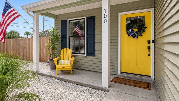 A house with a yellow door, a number 700 sign, an American flag, and a yellow Adirondack chair. - Gritz & Giggles, Southern Charm Meets Belly Laughs! Close to Parris Island (Port Royal)