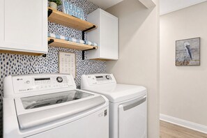 A laundry area with two LG Direct Drive washing machines, a 'STAINS' chart, and a shelf with towels. - Gritz & Giggles, Southern Charm Meets Belly Laughs! Close to Parris Island (Port Royal)