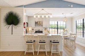 A kitchen with a central island, white cabinetry, and a hanging light fixture.