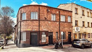 Ein Gebäude aus Ziegeln mit einer gewölbten Fassade, zahlreichen Fenstern und einem Motorrad davor.