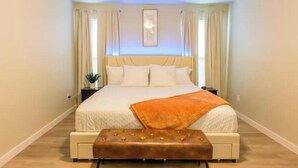 Un dormitorio con una cama grande, una mesita de noche y un adorno en la pared.