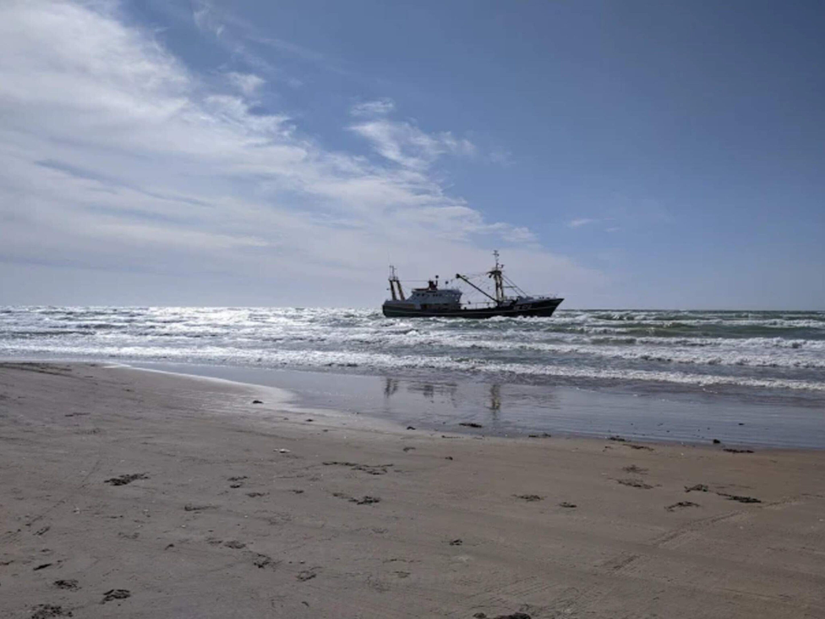 A beach with a ship in the water.