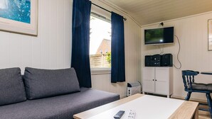 A modern living room with a grey sofa, a wooden coffee table, a TV, and a cabinet. - 6 Person Holiday Home in Lokken (Lokken)
