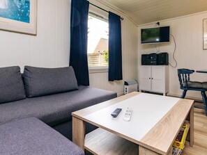 A modern living room with a grey sofa, a wooden coffee table, a TV, and a cabinet. - 6 Person Holiday Home in Lokken (Lokken)