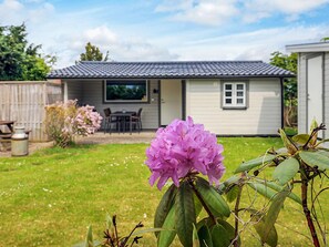 A residential house with a patio, a dining area, and a flower in the foreground.