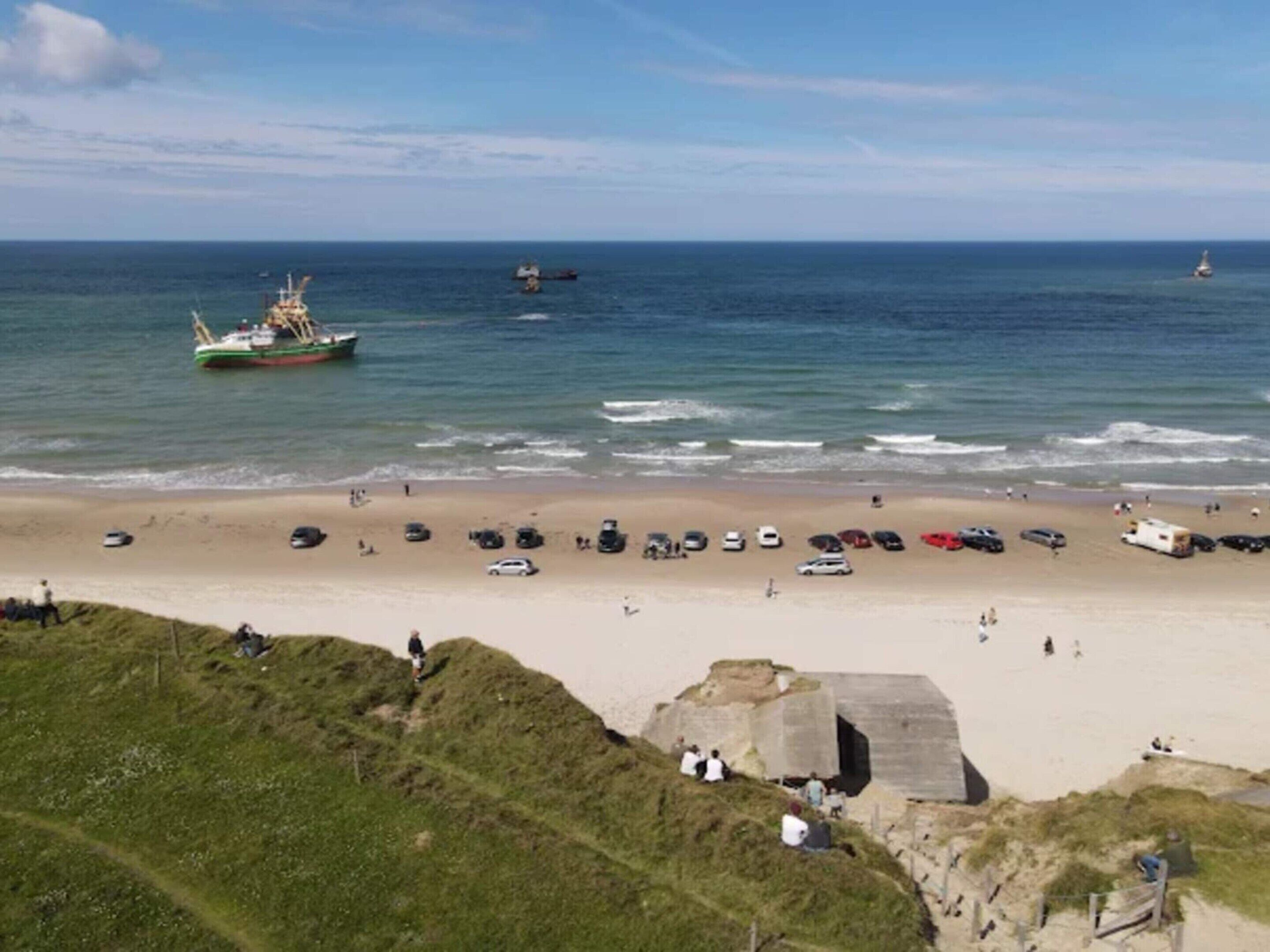 En strand med parkerede biler og et par personer.