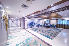 A hotel lobby with a long corridor, seating area with blue chairs, and a large patterned carpet. - Yangling International Conference & Exhibition Center Hotel (Xianyang)