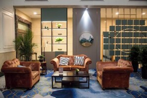 Un hall con un conjunto de sofás, una mesa de centro y un elemento decorativo en la pared.
