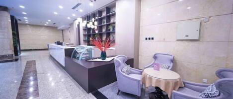 A modern reception area with a reception desk, seating, and a decorative plant.