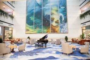 A lobby with a grand piano, comfortable seating, and a large painting on the wall. - Yangling International Conference & Exhibition Center Hotel (Xianyang)