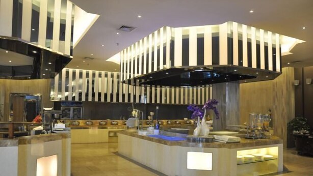 A modern hotel lobby with a central reception desk, a high ceiling with a unique light fixture, and a polished marble floor. - Yangling International Conference & Exhibition Center Hotel (Xianyang)