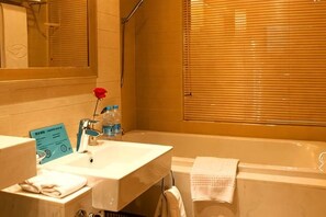 A bathroom with a bathtub, a sink, and a mirror. - Yangling International Conference & Exhibition Center Hotel (Xianyang)