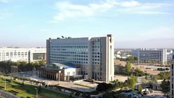 A multi-story building with a central courtyard, surrounded by greenery and a parking area.
