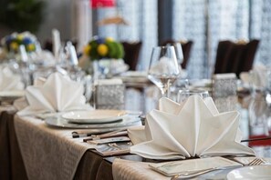 A dining table set with white napkins, silverware, and glassware, with a decorative centerpiece. - Yangling International Conference & Exhibition Center Hotel (Xianyang)